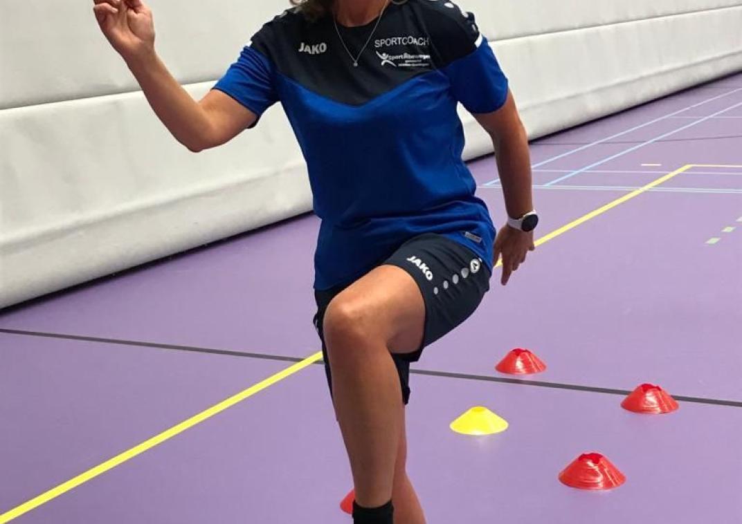 Foto van Buurtsportcoach Petra van den Engel die een oefening doet in een gymzaal.  