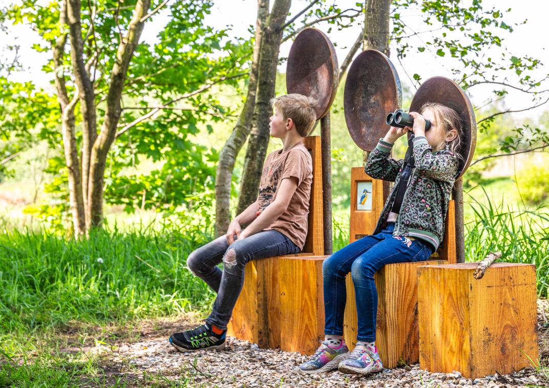 kinderen die met verrekijker vogels spotten