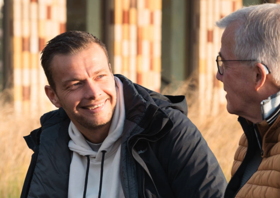 Twee mannen in gesprek in de zon bij het Huis van Cultuur en Bestuur in Hoogezand.