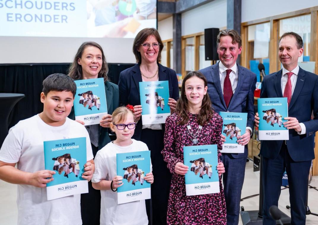 Kinderburgemeester Mara staat op een groepsfoto en presenteert samen met andere personen de sociale agenda van Nij Begun.
