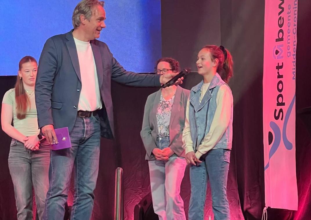 Kinderburgemeester Mara staat op het podium en spreekt in een microfoon. 