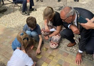 burgemeester, kinderburgemeester en 3 kinderen bekijken de onthulde Stolpersteine