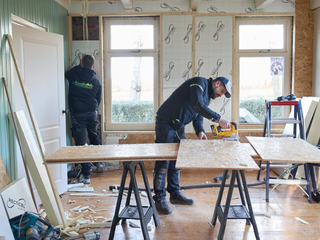Twee mannen werken aan de isolatie van het huis in Noordbroek.