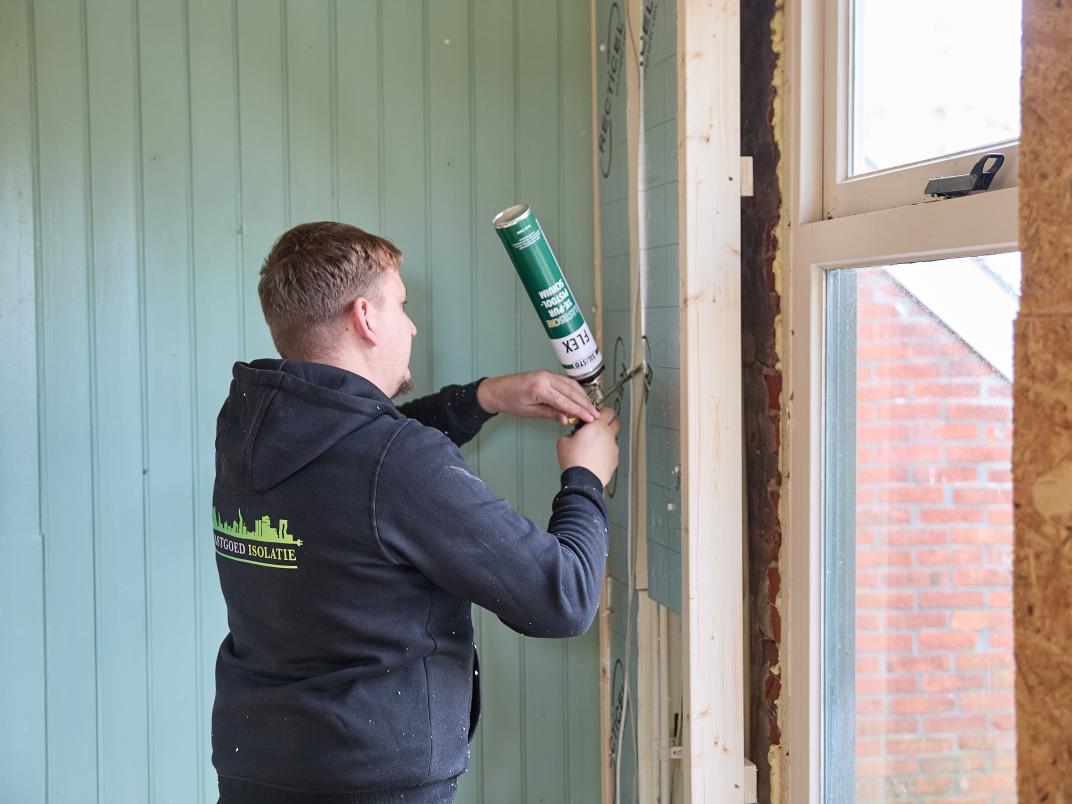 Een man werkt aan de isolatie van het huis in Noordbroek.