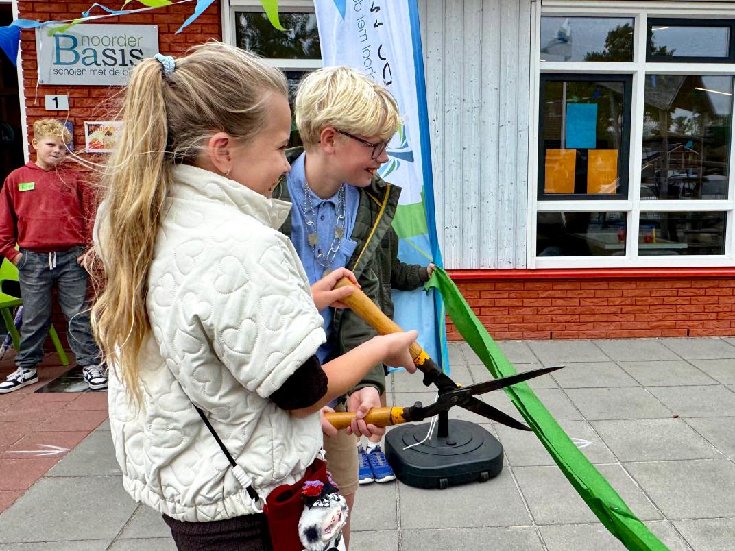 Kinderburgemeesters Myrthe Folkersma en Joep van Bergen openen het gezonde schoolplein door een lint door te knippen.