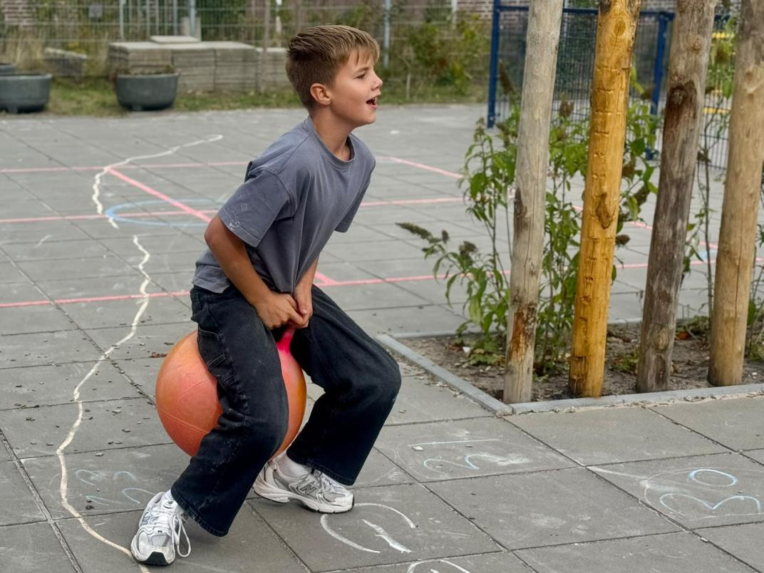 Jongetje op een skippybal op het schoolplein.
