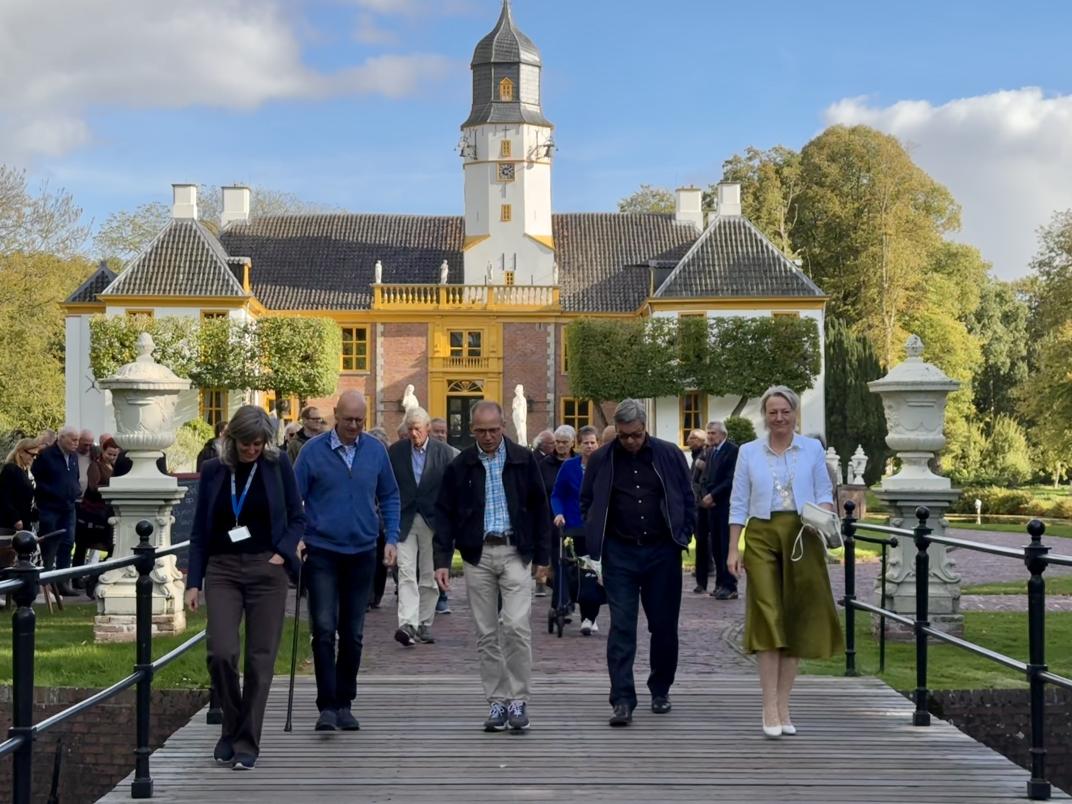 De groep die betrokken is bij de onthulling van de gedenksteen loopt voor de Fraeylemaborg op de brug.