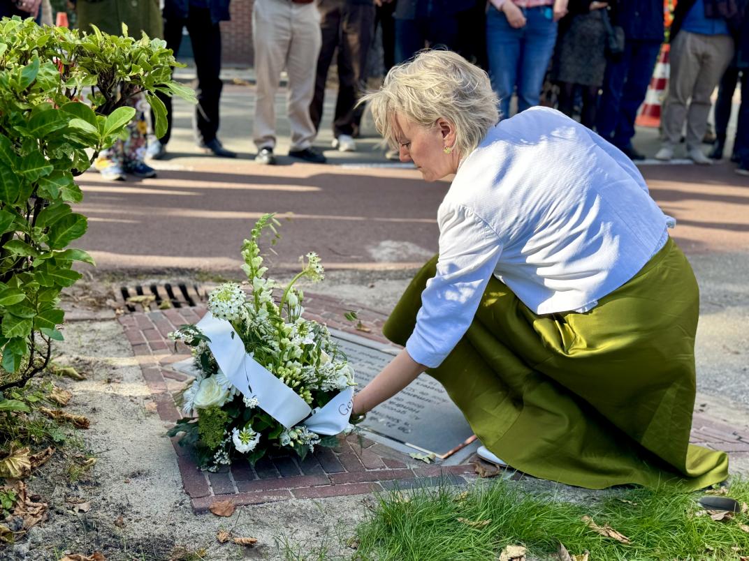 Burgemeester Erica van Lente legt een bloemstuk bij de gedenksteen in Slochteren