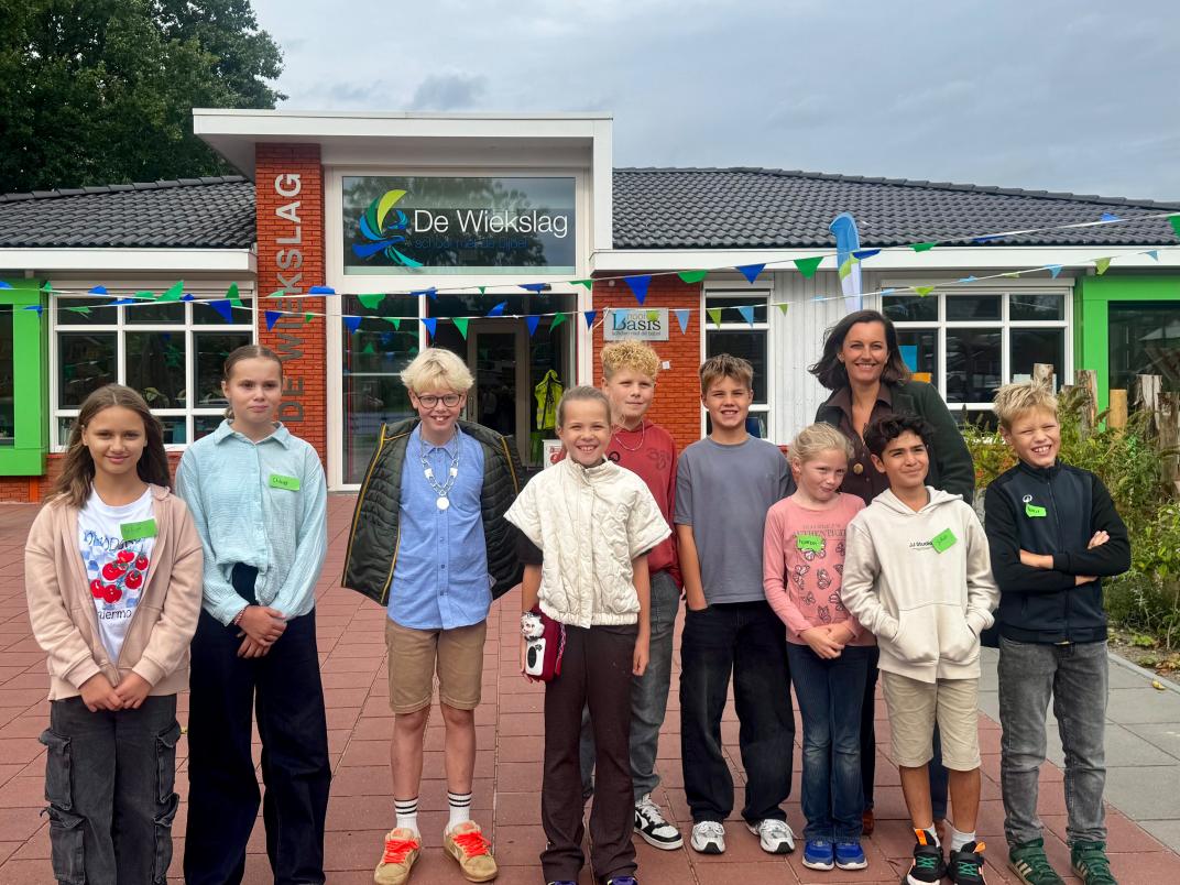 Myrthe, Joep, de directrice en andere kinderen staan voor basisschool De Wiekslag.