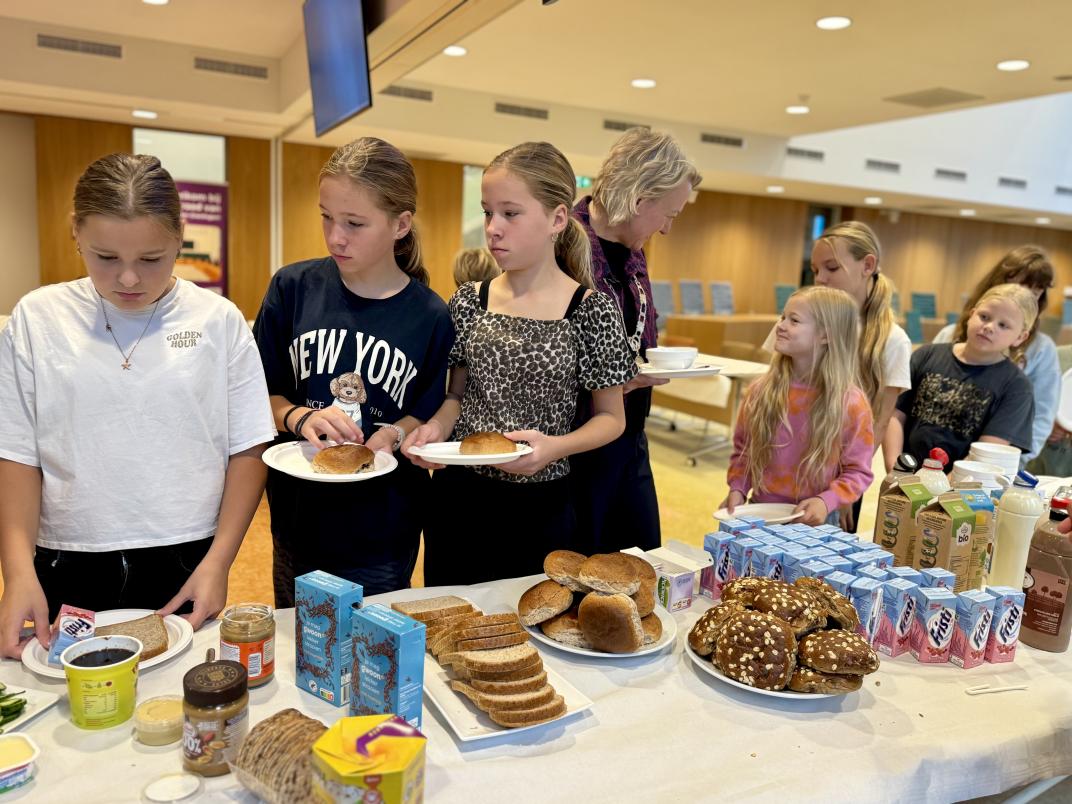 Kinderen van basisschool de Wegwijzer uit Slochteren staan bij het ontbijtbuffet met burgemeester Erica van Lente.