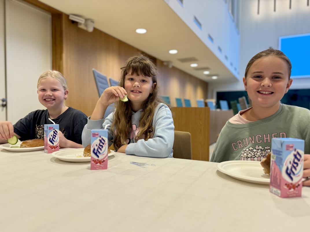 3 leerlingen van CBS de Wegwijzer eten samen hun ontbijt aan tafel.